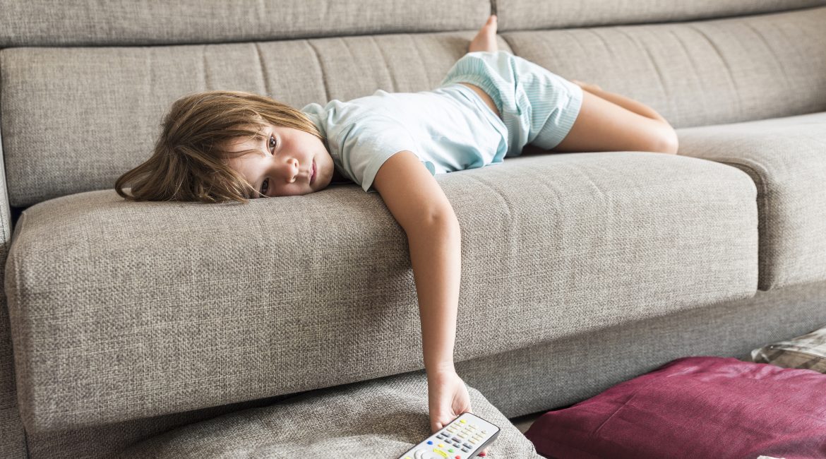 Little girl watching TV on the couch stretched