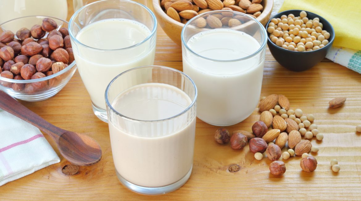Different vegan milks on a table. Hazelnut, rice, soya and almond milk. Substitute for dairy milk.