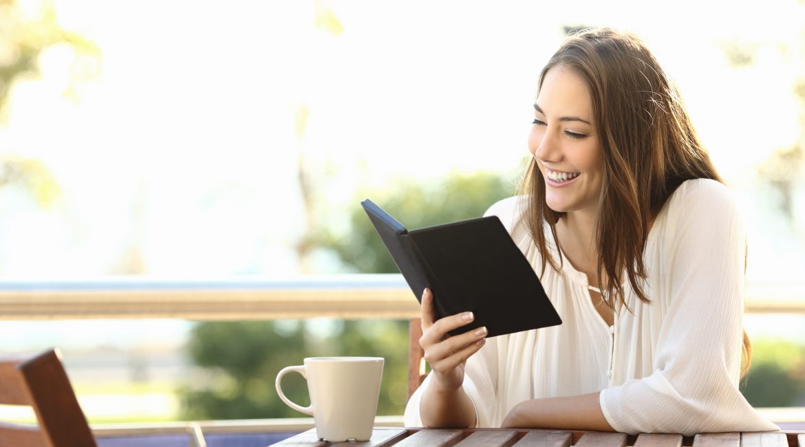 Woman relaxed reading a book in an ebook reader in a bar or at home
